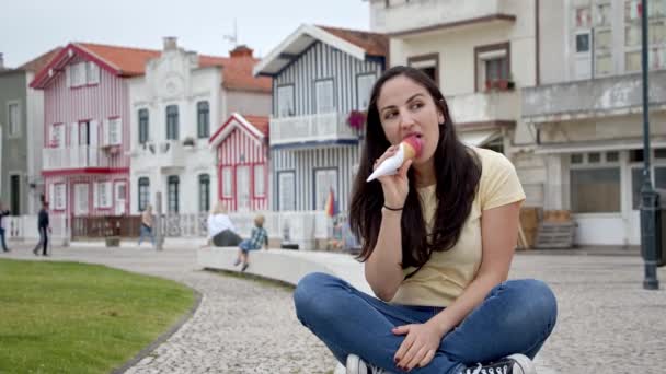 한 젊은 여자가 포르투갈 아베로 라는 평온 한 도시에서 2019 년 9 월 18 일 코스타 노바 해변에서 아이스크림을 핥는다 — 비디오