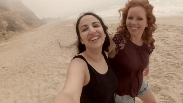 Two friends have fun filming themselves on a beach — ストック動画