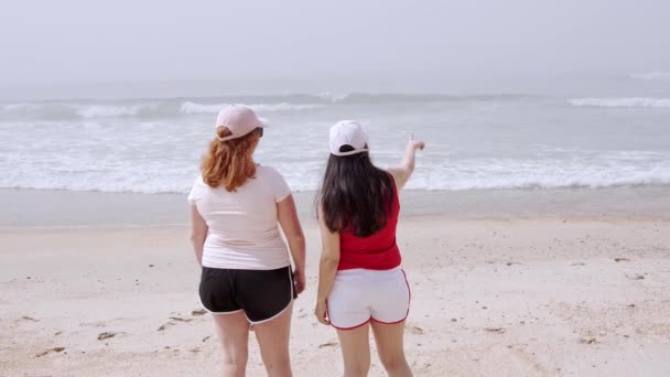 Menina bonita caminha em uma praia de areia à beira-mar — Vídeo de Stock