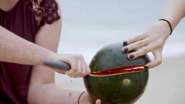 İki kız sahilde karpuz yiyor. Ağır çekim.