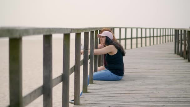 Νεαρή Γυναίκα Κάθεται Μια Ξύλινη Προβλήτα Στην Παραλία Αργή Κίνηση — Αρχείο Βίντεο