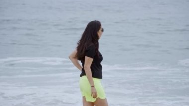 Güzel bir kız okyanus kıyısında kumlu bir sahilde yürüyor - yavaş çekim