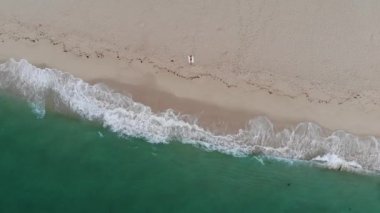 Okyanustaki kumlu bir plajın tepesinden aşağıya doğru. Hava aracı görüntüleri.