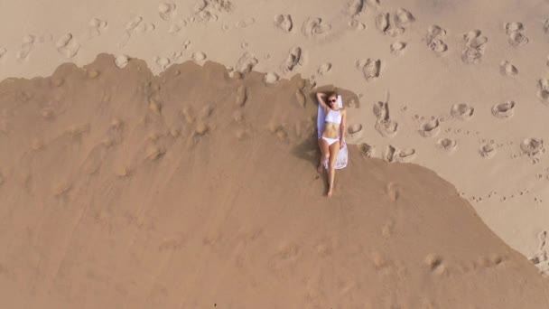 かわいいとセクシーな女の子がビーチで砂の中に横たわっています 空撮ドローン映像 — ストック動画