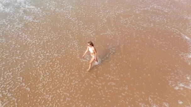 Sexy žena v bikinách kráčí přes písečnou pláž u oceánu - letecké drone záběry