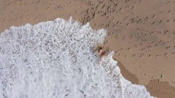 Cute and sexy girl lying in the sand at the beach - aerial drone footage