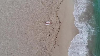 Okyanusun kumlu sahilinde tek başına güzel bir kız. Hava aracı görüntüsü.
