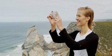 Young woman enjoys the view over the ocean at Cabo da Roca in Portugal - travel photography clipart