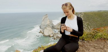 Beautiful woman relaxes at Cabo da Roca in Portugal - Sintra Natural Park - travel photography clipart