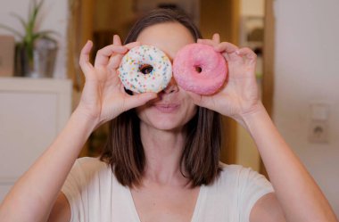 Genç bir kadın tatlı şekerli çörekler yiyor.