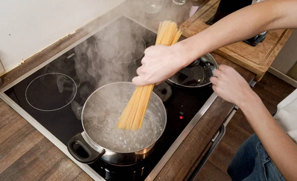 Young woman cooks spaghetti in the kitchen — Stock Photo, Image