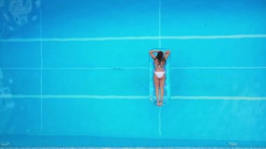 Güzel kız yüzme havuzundaki şişme yatakta yatıyor.