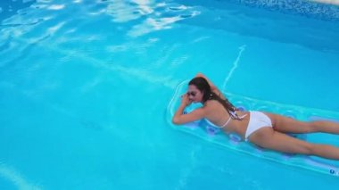 Genç ve seksi kadın yazın havuzda dinleniyor.