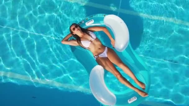 Сексуальная девушка наслаждается солнцем в кристально чистой воде бассейна — стоковое видео