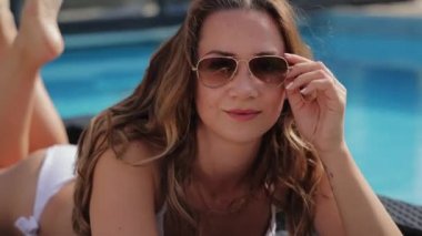 Yüzme havuzunda güneşlenen bikinili seksi kadın.