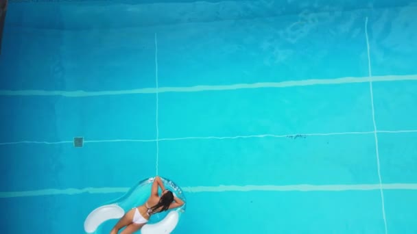 Красива дівчина лежить на повітряному матраці в басейні — стокове відео