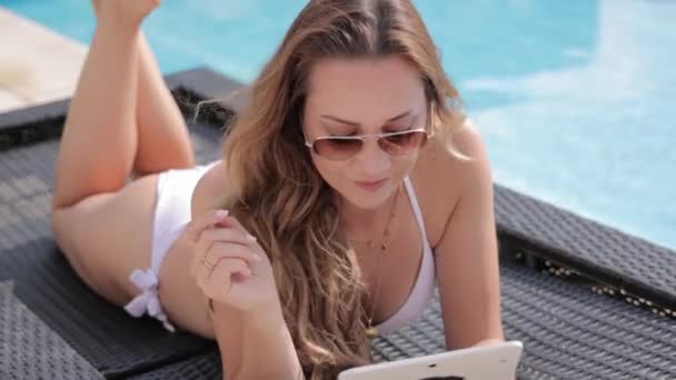Junge Frau im Bikini entspannt mit Tablette am Pool — Stockvideo