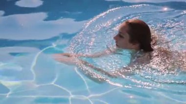 Seksi kadın havuzda yüzüyor.