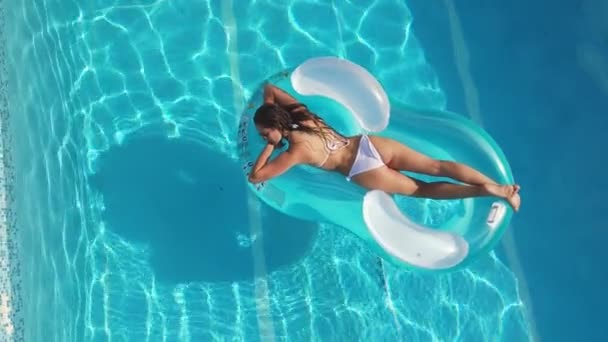 Mooi meisje ligt op een lucht matras in het zwembad — Stockvideo