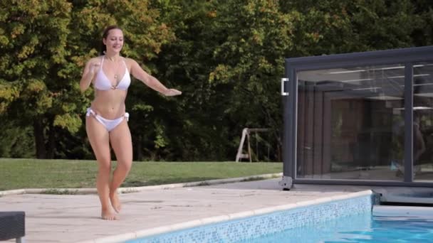 비키니를 입은 섹시 한 여자가 느린 동작으로 수영장에 뛰어 든다 — 비디오