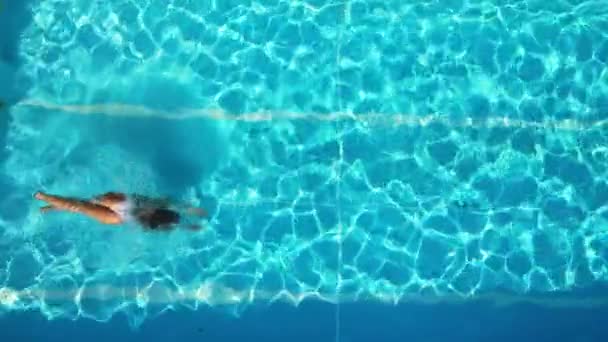 Young woman enjoys swimming in the cool water of a pool in summertime — Stock Video