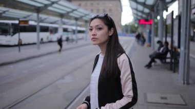 Genç Asyalı kadın şehirde tramvayı bekliyor.
