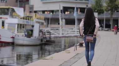 Genç Asyalı kadın nehir boyunca yürüyor.