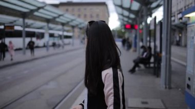 Genç Asyalı kadın şehirde tramvayı bekliyor.