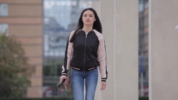 Mujer asiática joven camina sobre una plaza en una ciudad — Vídeos de Stock
