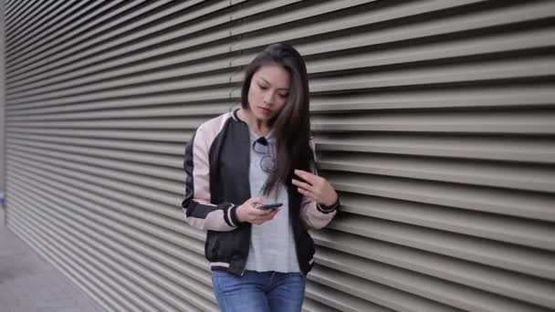 Jovem mulher asiática escreve mensagens de texto em seu telefone — Vídeo de Stock