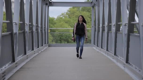 Mujer asiática joven camina sobre un puente en una ciudad — Vídeos de Stock