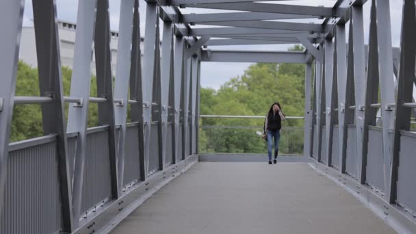 Jeune femme asiatique marche sur un pont dans une ville — Video