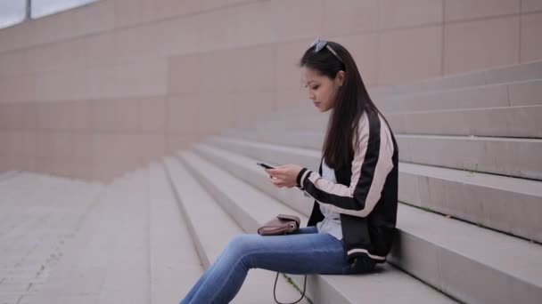 Jovem mulher asiática escreve mensagens de texto em seu telefone — Vídeo de Stock