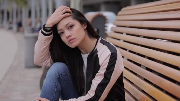 Pretty Asian girl sits on a bench and relaxes — Stock Video