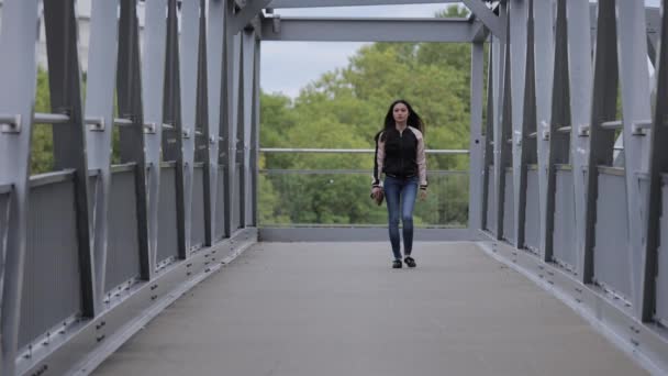 Mujer asiática joven camina sobre un puente en una ciudad — Vídeos de Stock