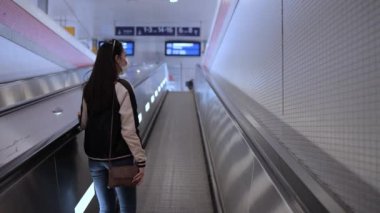 Tren istasyonunda tren bekleyen Asyalı genç bir kadın.