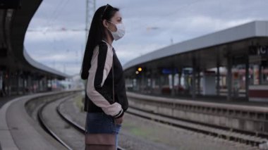 Tren istasyonunda tren bekleyen Asyalı genç bir kadın.