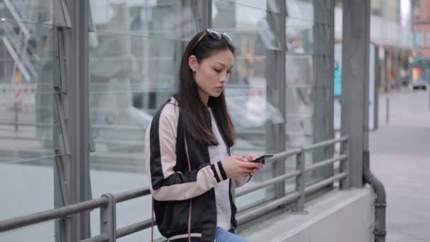 Młoda Azjatka pisze SMS-y na swoim telefonie — Wideo stockowe