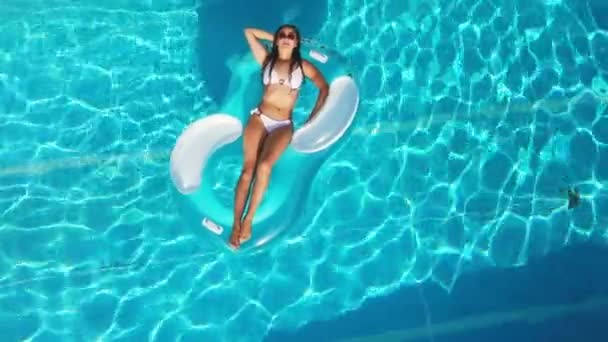 Young and sexy woman relaxes in a pool in summer — Stock Video