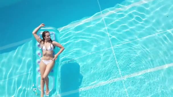Pretty girl lies on an air mattress in the swimming pool — Stock Video