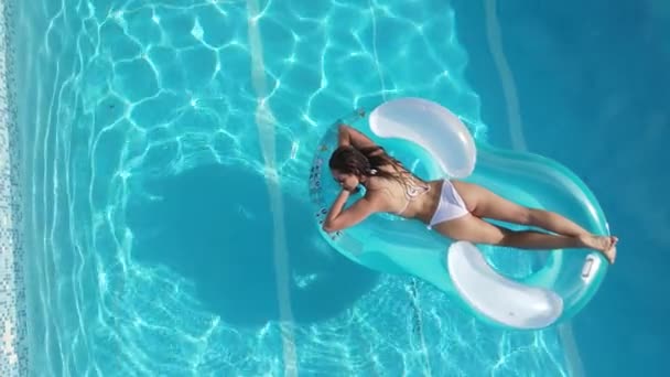 Sexig flicka njuter av solen i det kristallklara vattnet i en pool — Stockvideo