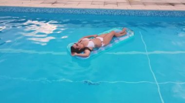 Genç ve seksi kadın yazın havuzda dinleniyor.