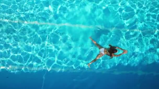 Молода жінка насолоджується плаванням у прохолодній воді басейну в літній час — стокове відео