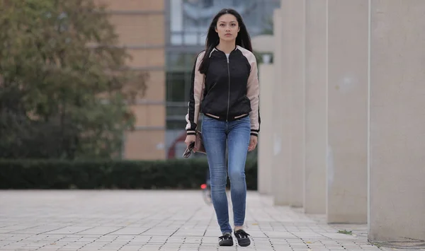 Mujer asiática joven camina sobre una plaza en una ciudad — Foto de Stock