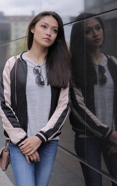 Genç Asyalı kadın şehir merkezinde kameraya poz veriyor.