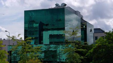 LUXEMBOURG, EUROPE - 1 Eylül 2025 - Lüksemburg, Avrupa 'nın başkenti Lüksemburg' daki bulutlu gökyüzünü yansıtan modern bir binanın yeşil cam cephesi