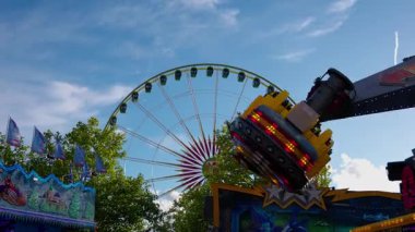 LUXEMBOURG, EUROPE - SEPTEMBER 1, 2025 - Avrupa, Lüksemburg 'daki Schueberfouer lunaparkında dönme dolap ve bayraklarla yüksek hızda dönen Atlıkarınca