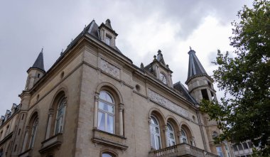 Lüksemburg 'da tarihi bir binanın alçak açılı görüntüsü. Karmaşık mimarisini ve saat kulesini bulutlu gökyüzüne karşı sergiliyor.