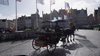 BRUGES, BELGIUM - 15 Eylül 2025 - Markt Meydanı, Bruges, Belçika 'daki kaldırım taşı caddesinde turist taşıyan at arabası