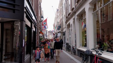 HAGUE, NETHERLANDS - 14 Eylül 2025 - Lahey 'in her iki tarafında da bisikletleri olan insanlar dar bir alışveriş caddesinde yürüyorlar
